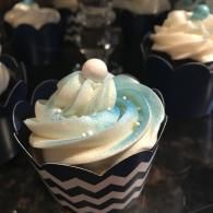 Blue-and-white swirled cupcake with a white pearl topper in a chevron wrapper