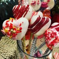 Heart-shaped red and white candy pops with sprinkles in a glass jar