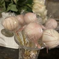 Assorted pale pink and white decorative flower-like ornaments in a glass vase or container