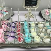 Tray of pastel cake pops and decorated treats on a mirrored dessert stand