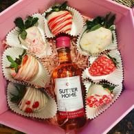 Pink gift box with a mini Sutter Home wine bottle surrounded by chocolate-covered strawberries and treats