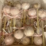 Box of pastel pink and white decorative ornaments wrapped in clear plastic with gold beaded accents