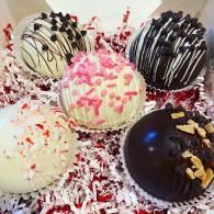 Assorted chocolate-dipped cake pops and candy-coated treats on shredded paper confetti