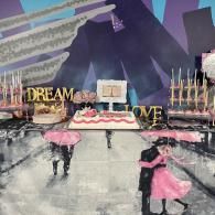 Decorative dessert display with pink-and-gold cake, candles, and dancers on a glossy stage backdrop