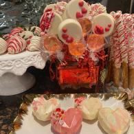 Candy and dessert buffet with red, pink, and white treats on trays and in a glass container