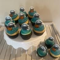 Teal and gold frosted cupcakes arranged on a white cake stand and tray