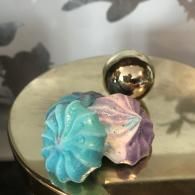 Turquoise and lavender flower-shaped candies on a reflective gold surface