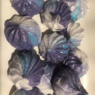 Purple and blue iridescent ruffled fabric flowers clustered together on a white background