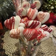 Heart-shaped red-and-white striped cake pops in a glass vase, decorated for a festive display