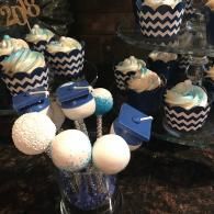 Blue-and-white chevron cupcakes and cake pops arranged on a dessert table with decorative boxes