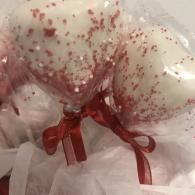 Clear balloon with red confetti and a red ribbon bow inside tissue paper packaging