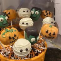 Halloween cupcakes with orange, green, and white icing faces in orange wrappers
