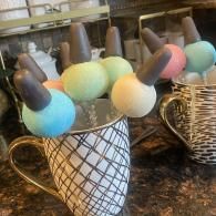 Mug of colorful marshmallow bunny pops arranged in a basket on a kitchen counter