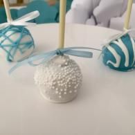 White and teal decorated candy balls with ribbon bows on a white table