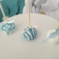 Blue and white striped cake pops on sticks displayed on a white table