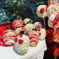 Red and white striped chocolate-covered treats topped with cherries on a white platter