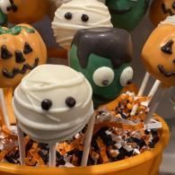 Halloween cake pops in an orange basket, decorated as pumpkins, ghosts, and monsters