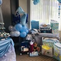 Blue and gray balloon-filled gift display with presents and a “CAMDEN” sign by a window