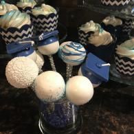 Decorated cake pops and round treats in blue, white, and black on a countertop