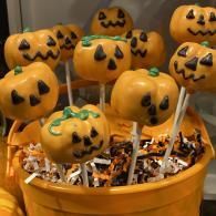 Halloween cake pops with jack-o’-lantern faces in a bucket of candy wrappers
