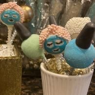 Decorated cake pops in a glass and paper cup, with colorful faces and sprinkles