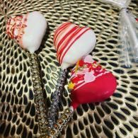Three decorated heart-shaped lollipops on a patterned surface