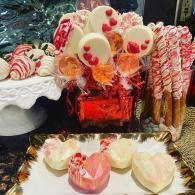 Candy dessert display with red, white, and pink treats on trays and sticks