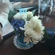Small bouquet of blue and white flowers in a decorative lace vase on a table