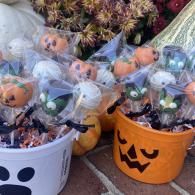 Halloween treat buckets with ghost and jack-o’-lantern faces, filled with wrapped goodies and pumpkins