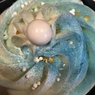 Blue glass swirl with a white pearl-like sphere and small beads on a dark background