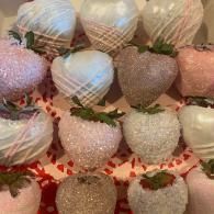 Rows of pastel and white strawberries on a decorative tray, wrapped in patterned mesh and lined with green leaves