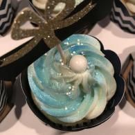 Blue-and-white swirled cupcake with glittery topping in a black wrapper