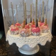 Elegant dessert stand with pink and white cake pops and gold sprinkles on a white pedestal cake stand