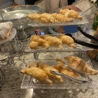 Tray stands with assorted croissants and pastries on a marble counter at a buffet.