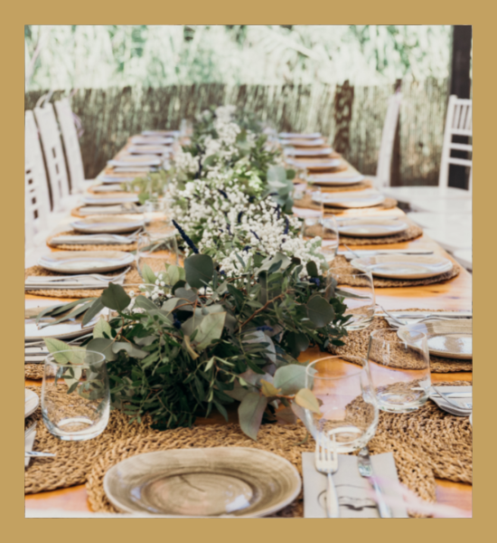 Elegant outdoor dining table with floral centerpiece, plates, glasses, and woven chargers in a garden setting