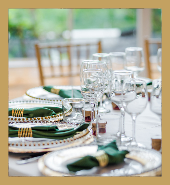 Elegant dining table set with white plates, green napkins, and wine glasses by a window