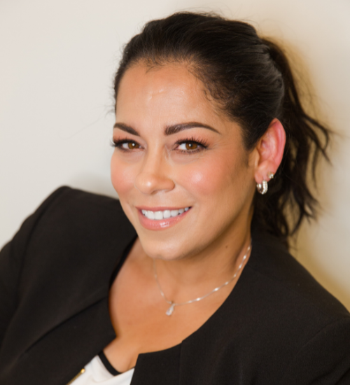Portrait of a smiling woman in a black blazer against a light background