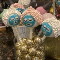 Muffin pops with blue faces and white curls in a glass jar of gold beads