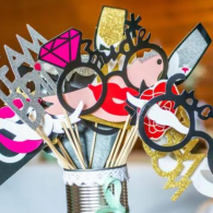 Colorful photo booth props in a tin cup against an orange background