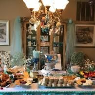 Dining table set with assorted desserts and dishes under a chandelier in a formal room