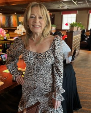 Smiling woman in a patterned dress standing in a restaurant