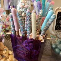 Purple bucket holding pastel candy-themed sticks at a colorful display table