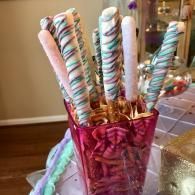 Colorful striped candy sticks in a pink glass vase on a table