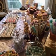 Candy buffet with jars of colorful sweets, lollipops, and cupcakes on a decorated table
