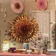 Decorated party table with gold and pink fan decorations in front of a white door