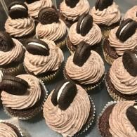 Tray of chocolate cupcakes with swirled frosting and Oreo cookie halves on top