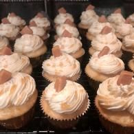 Rows of frosted cupcakes in paper liners on a bakery rack