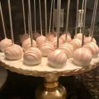 Pink striped cake pops on sticks arranged on a gold stand