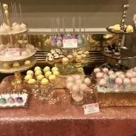 Dessert buffet with assorted pastel macarons and treats displayed on tiered trays and a table