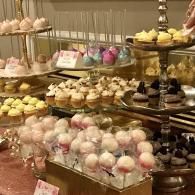 Elegant dessert display with cupcakes and pastel sweets on tiered stands and trays